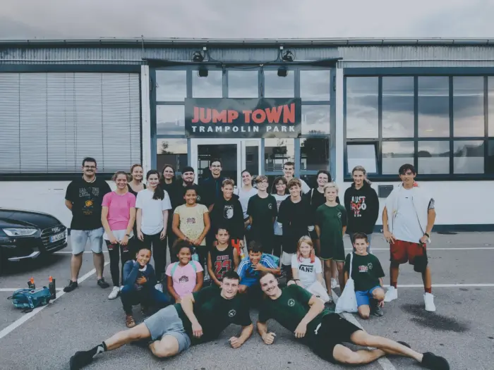 Die ganze Gruppe steht und liegt für ein Foto vor dem Eingang des Trampolinparks Jump Town.