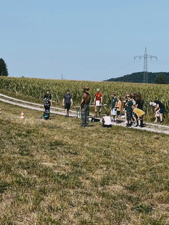 Eine Gruppe läuft über einen Feldweg zwischen hohen Maisfeldern.